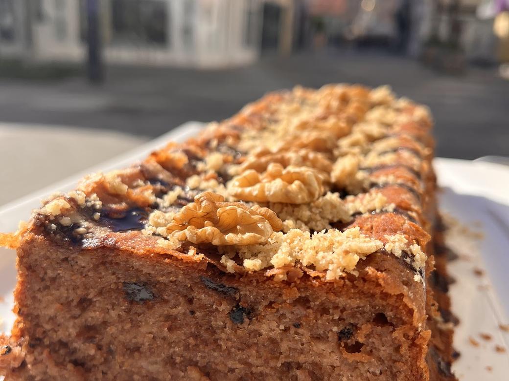 Dicke Scheibe hausgebackenes Bananenbrot mit Nüssen und Streuseln auf einem weißen Teller